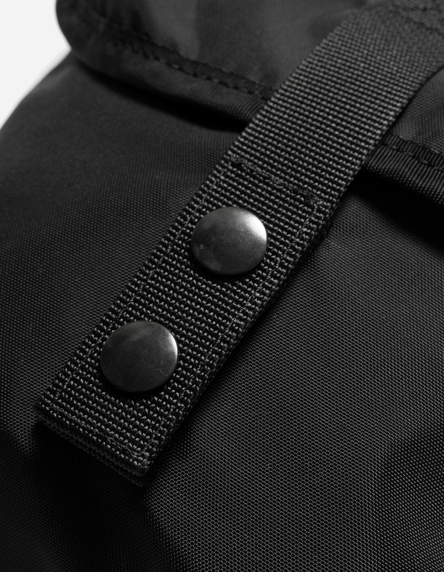 Close-up of a black jacket with buttons and a strap on a white background