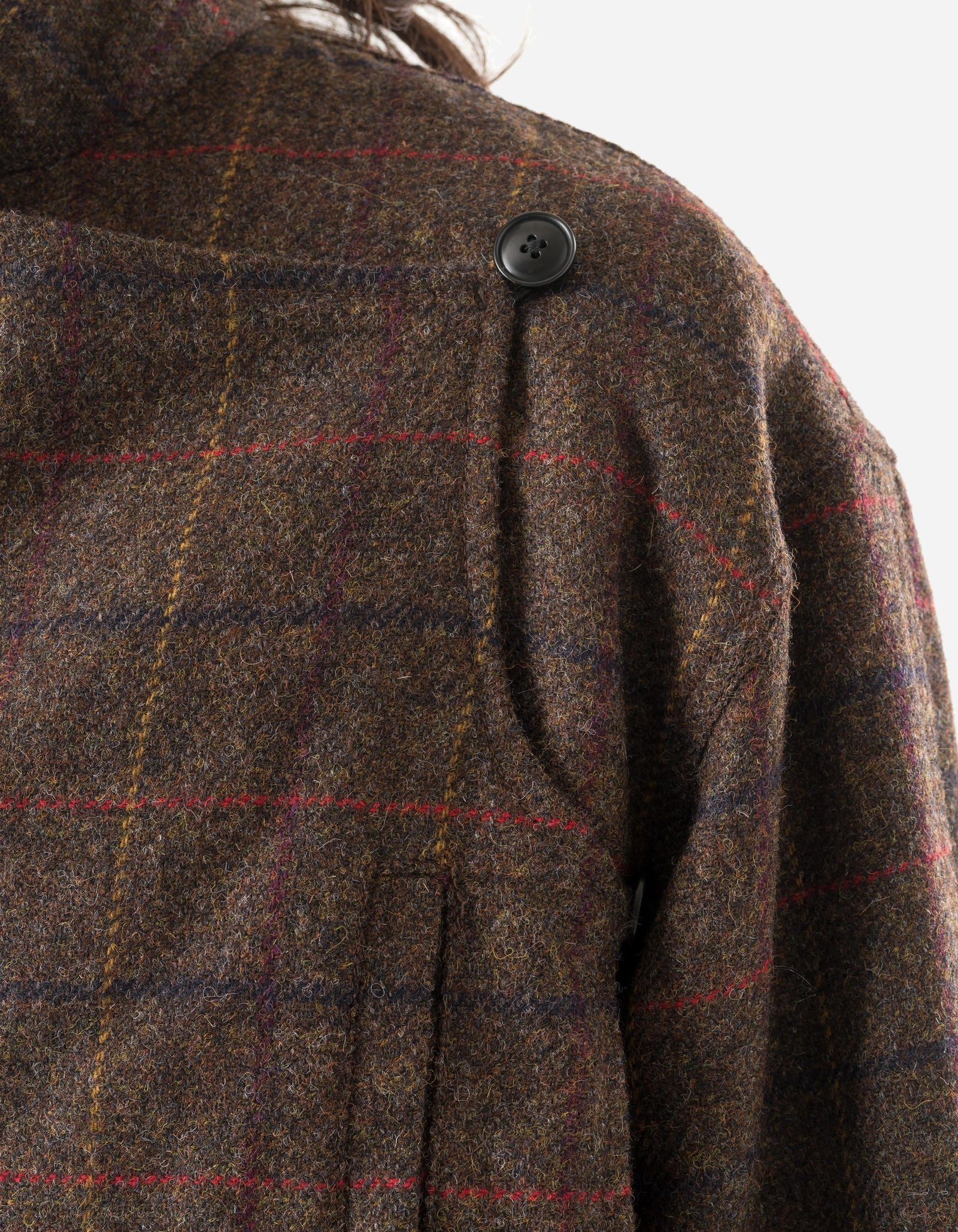 Close-up of a brown plaid coat with a button on a white background