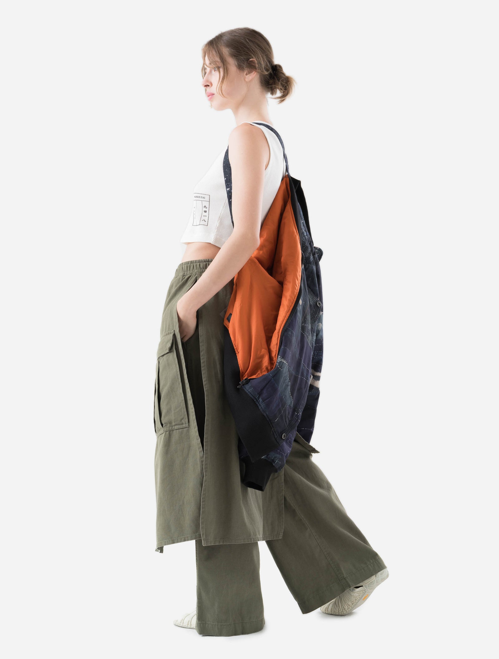 Person wearing a maharishi jacket over a white shirt with an orange interior, standing against a white background.