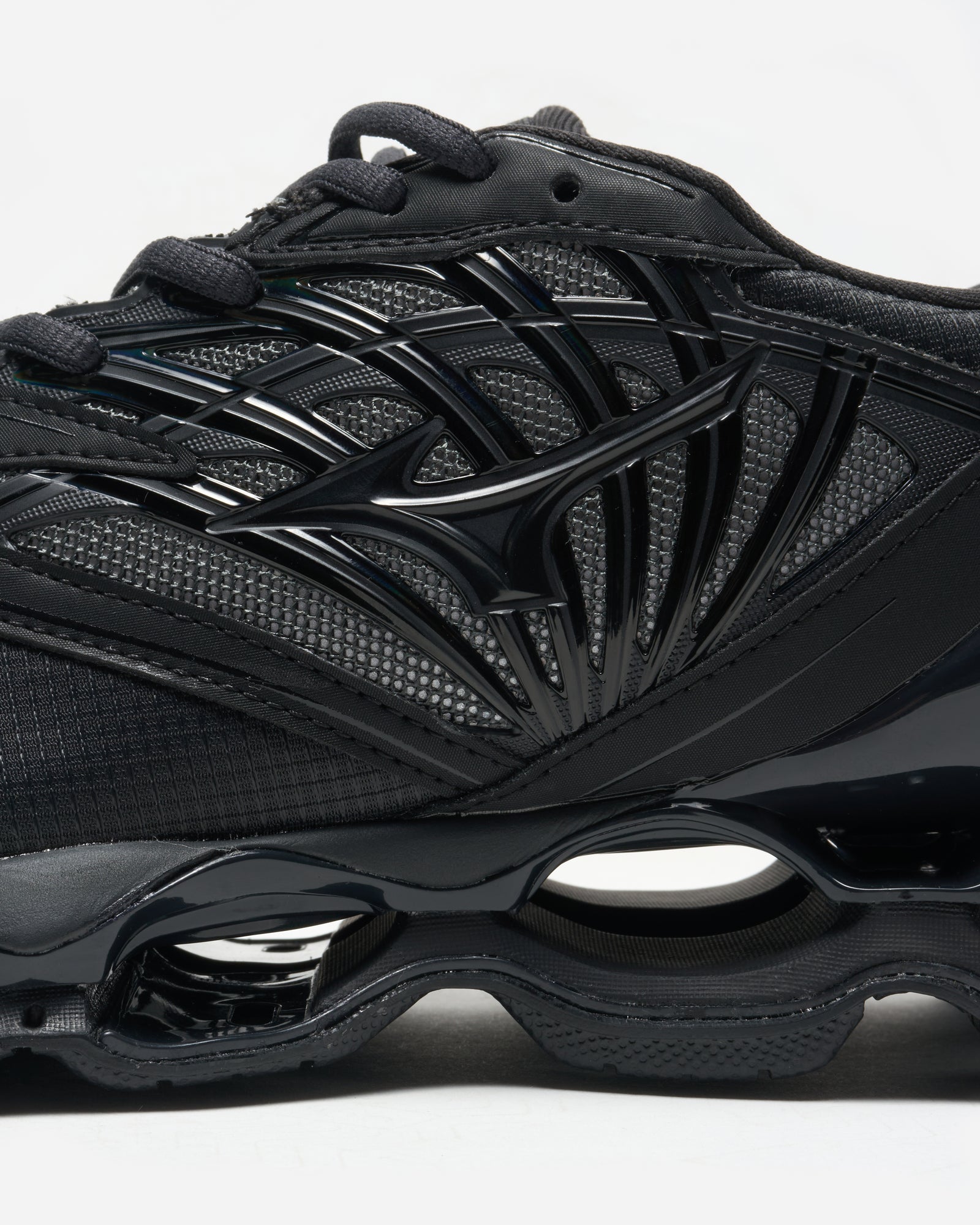 Black athletic shoe with unique sole design on a white background
