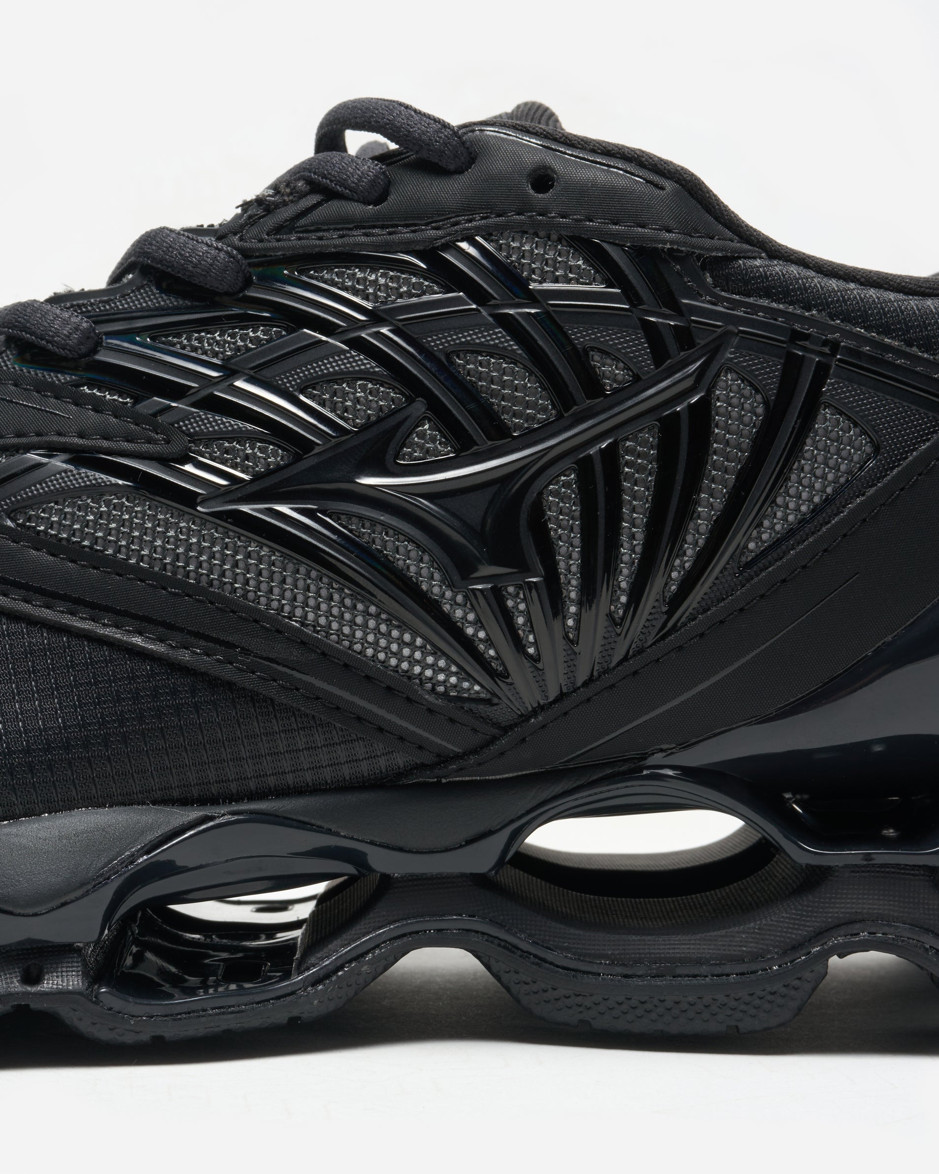 Black athletic shoe with unique sole design on a white background