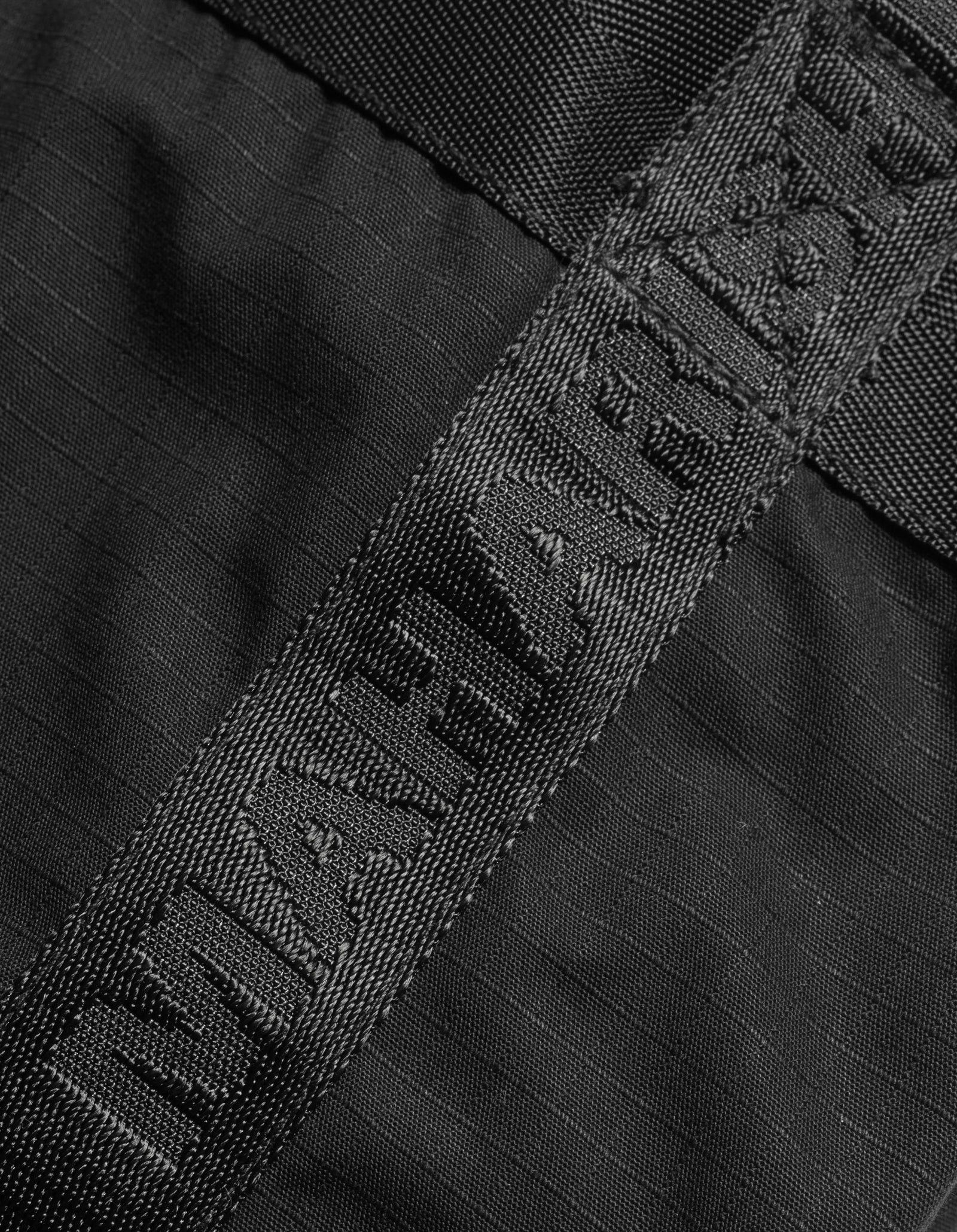 Close-up of a black belt with a brand logo on a textured black background