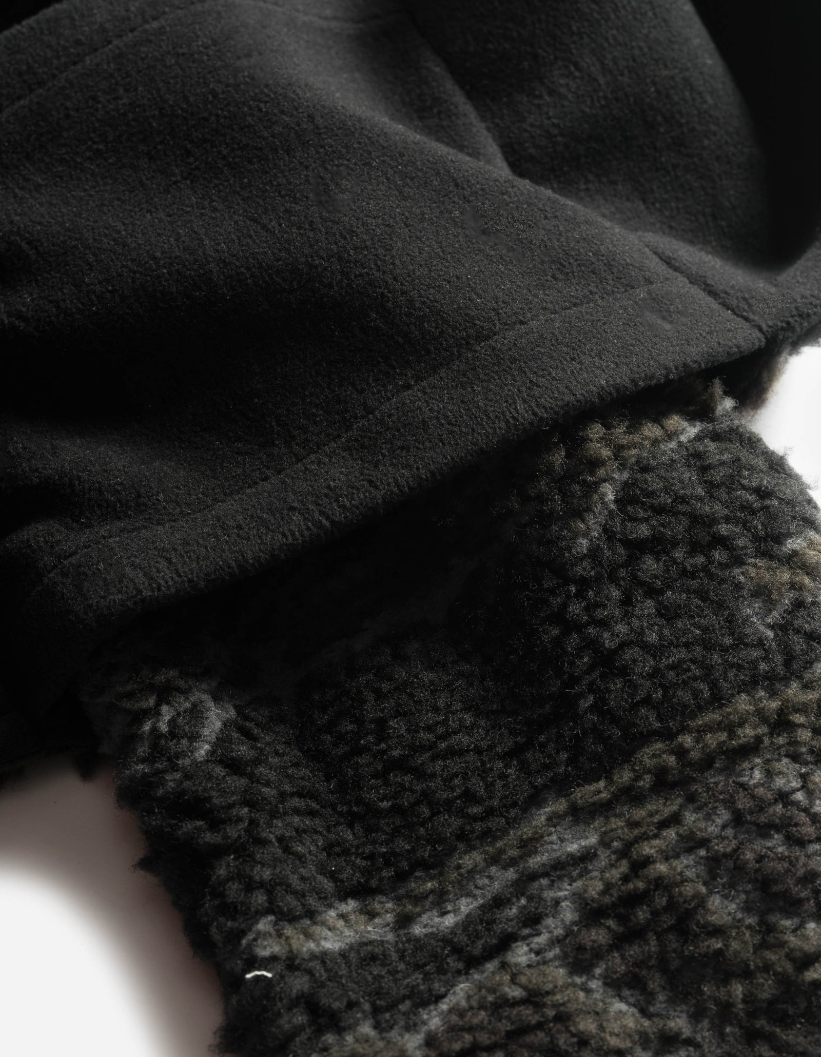 Close-up of a textured black fabric with a patterned gray fabric underneath.