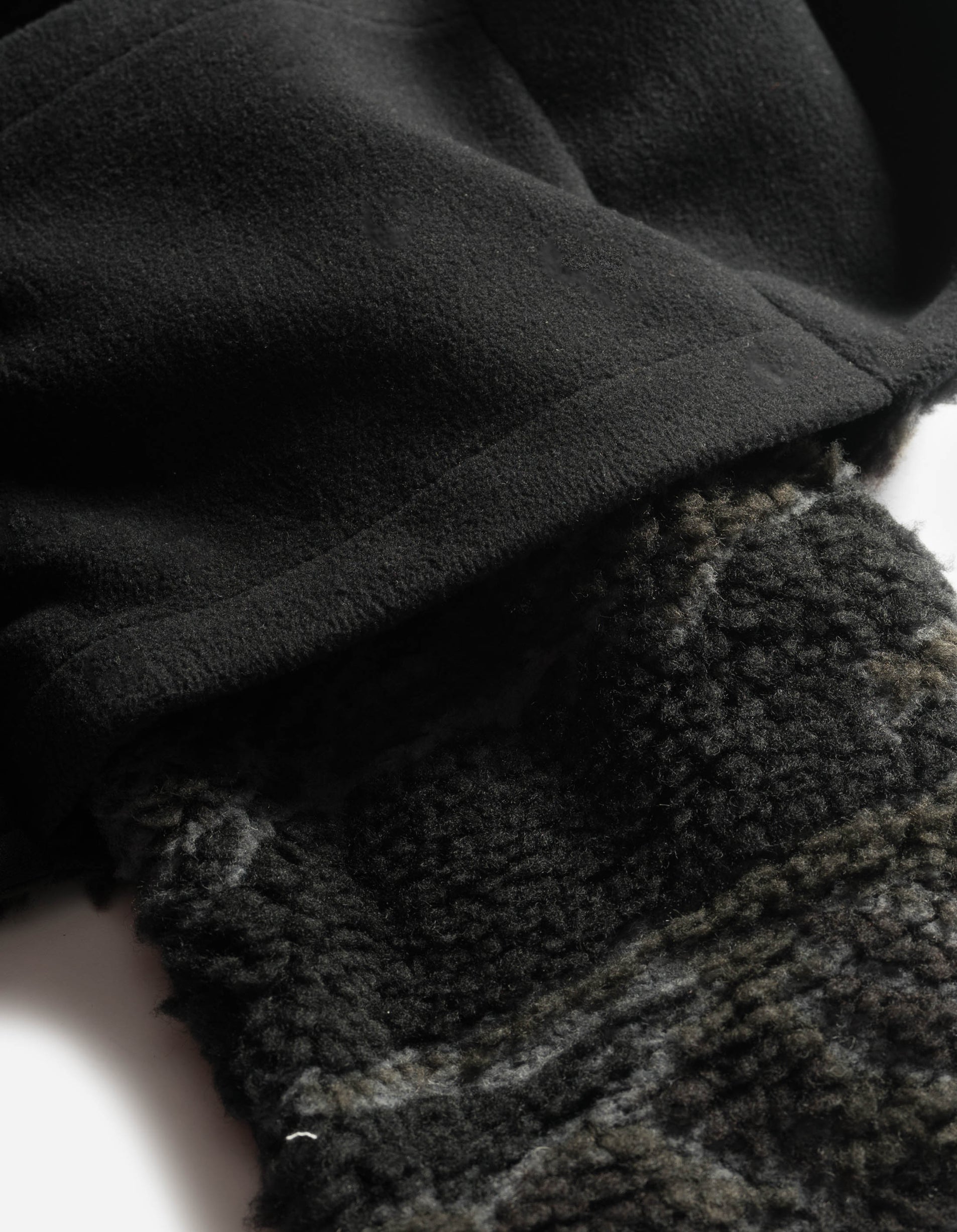 Close-up of a textured black fabric with a patterned gray fabric underneath.