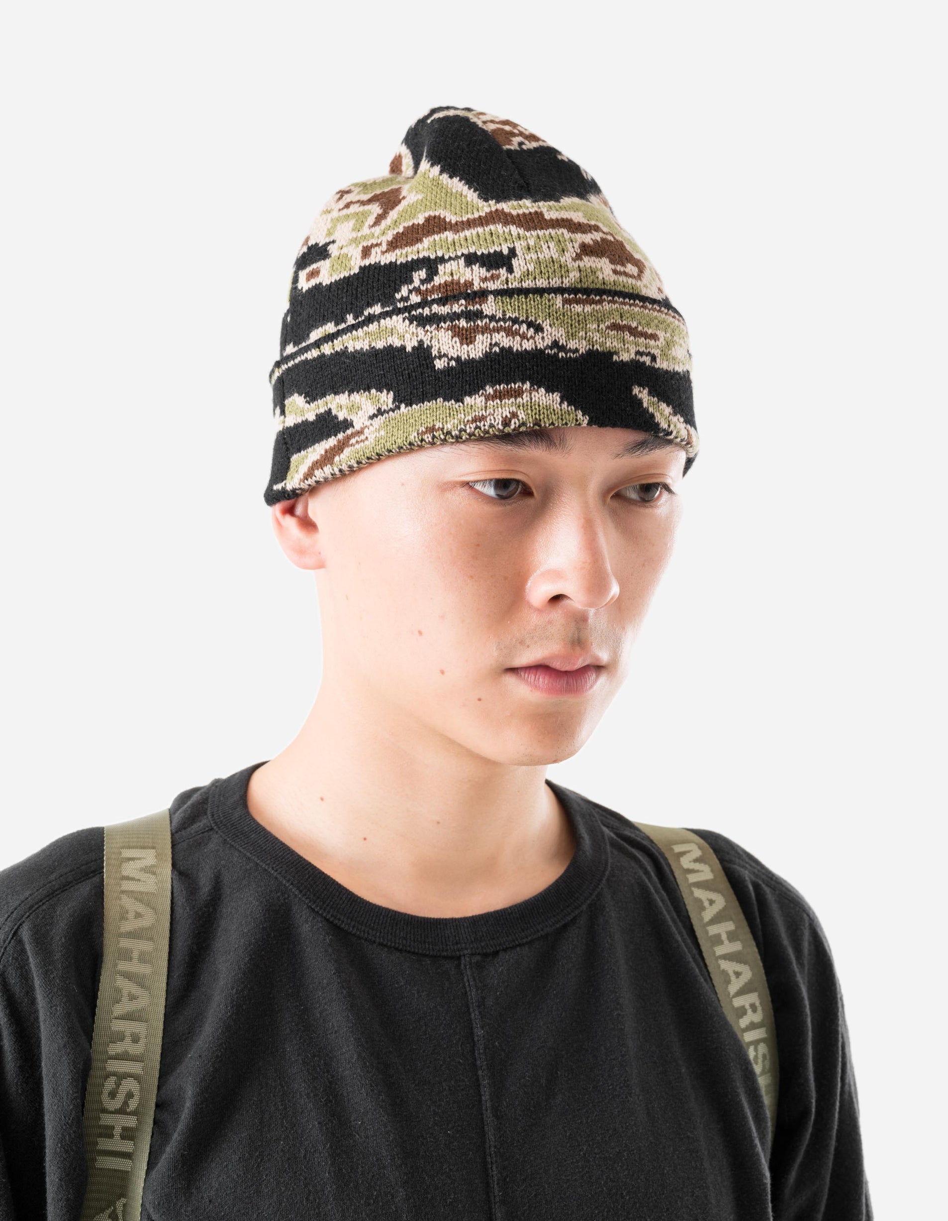 Person wearing a camouflage beanie and black shirt with 'MAHARISHI' branding.