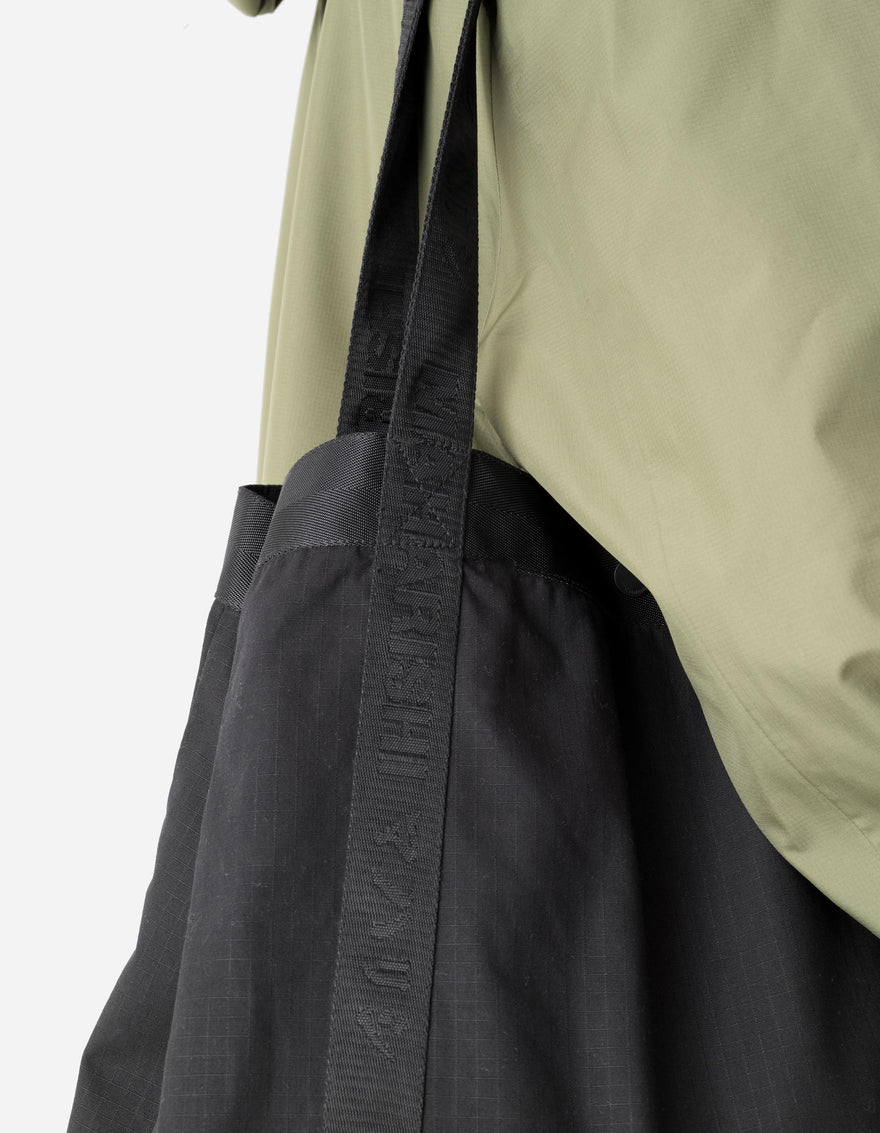 Black tote bag with a beige jacket on a white background