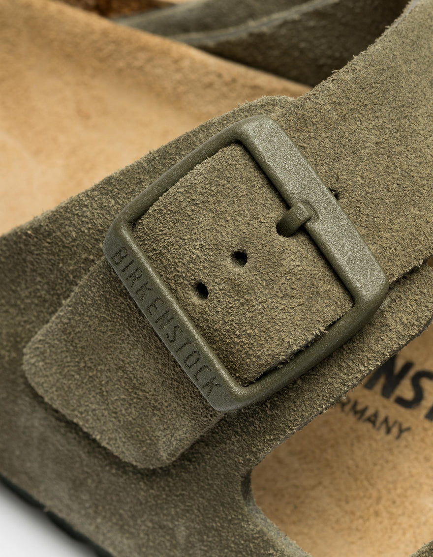 Close-up of a suede sandal with a buckle, featuring the Birkenstock brand.