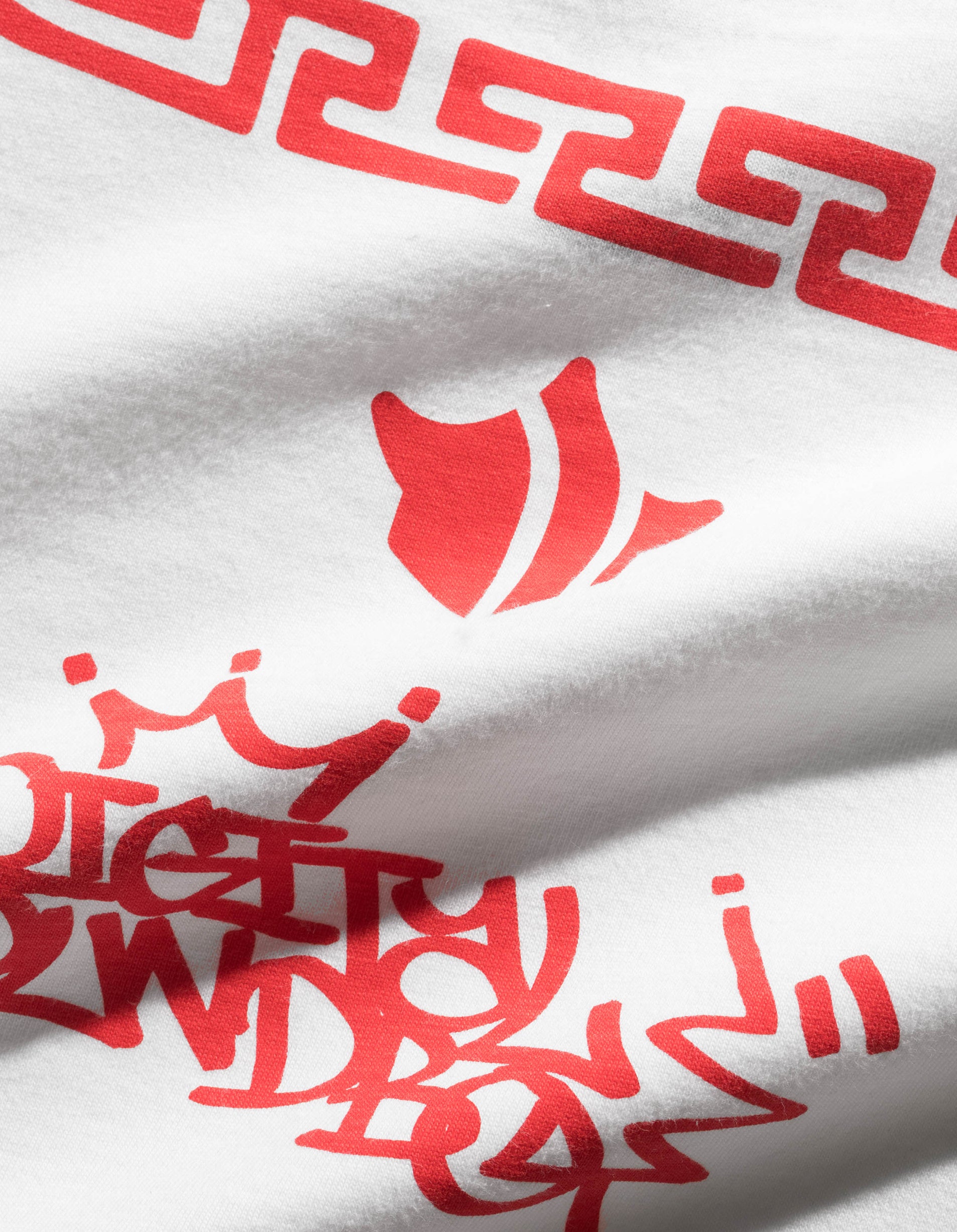 Close-up of a white fabric with red geometric patterns and text.