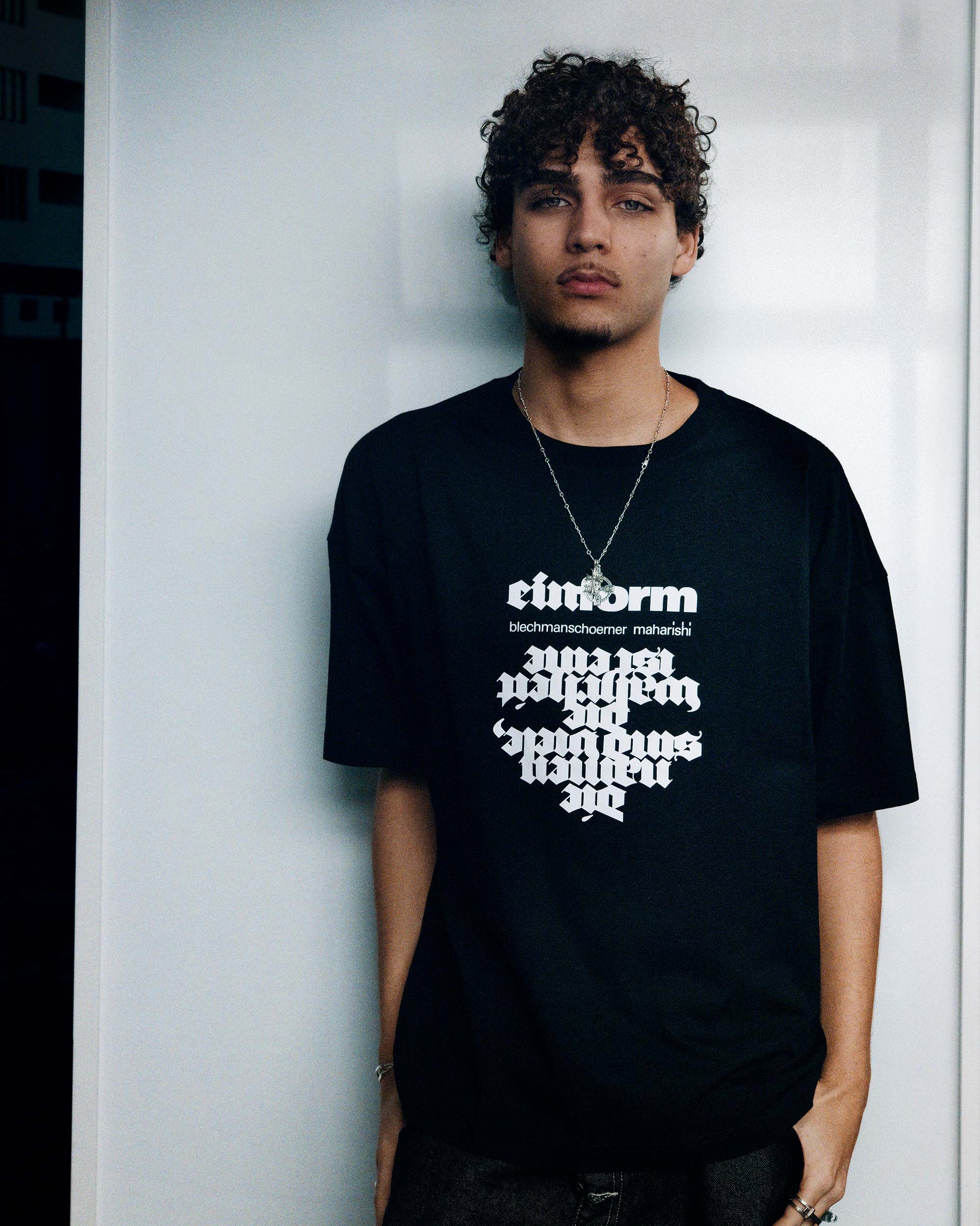 Person wearing a black t-shirt with white text against a plain background