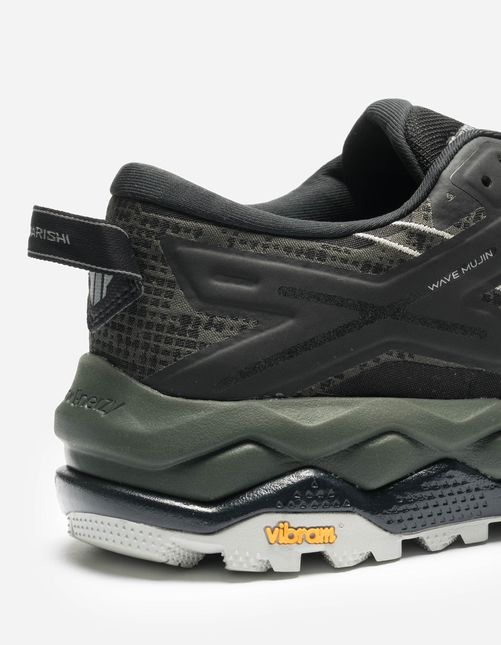 Close-up of a black and green athletic shoe with 'Vibram' branding on a white background