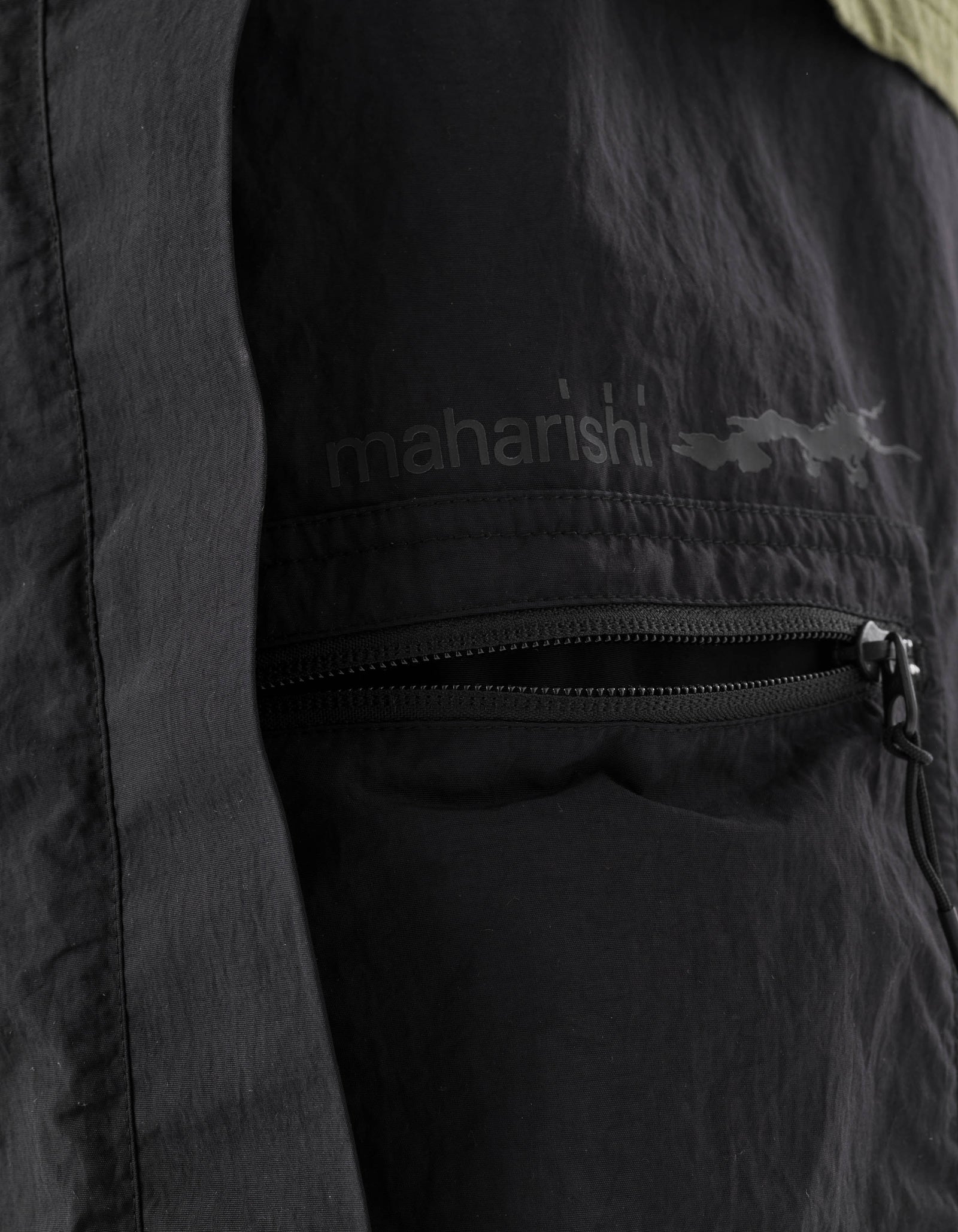 Black jacket with 'maharishi' branding on a dark background