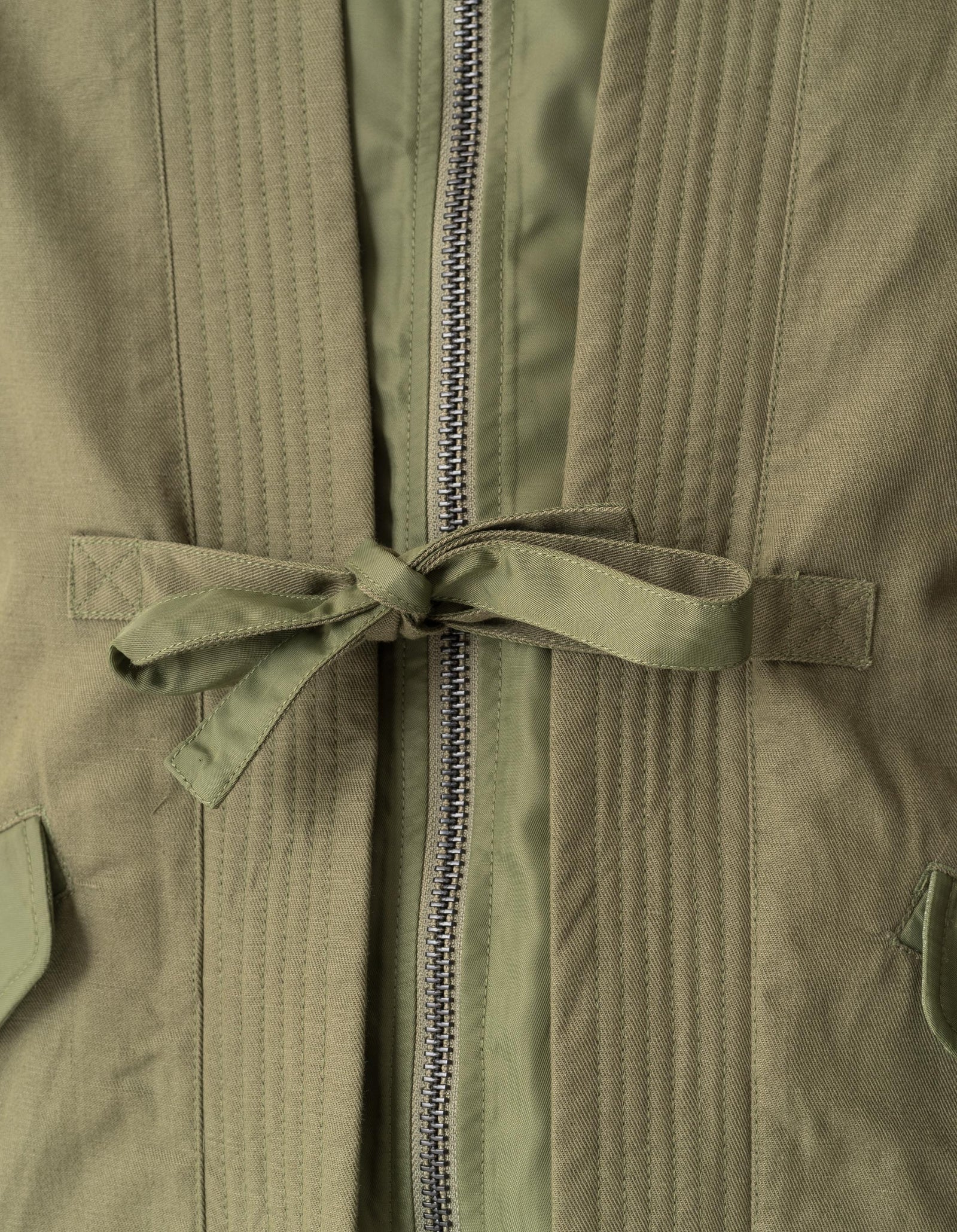 Close-up of a green jacket with a zipper and tie detail.