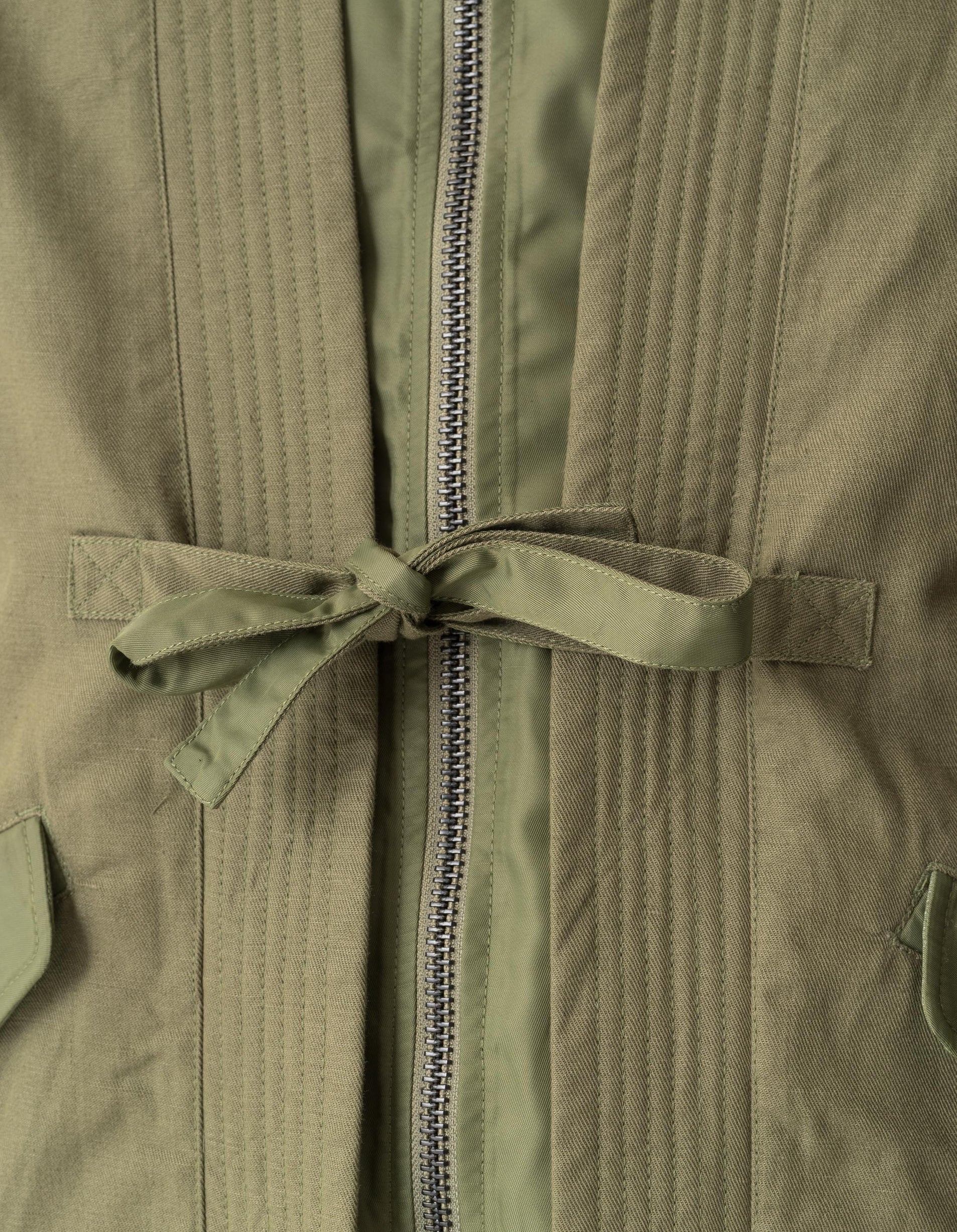 Close-up of a green jacket with a zipper and tie detail.