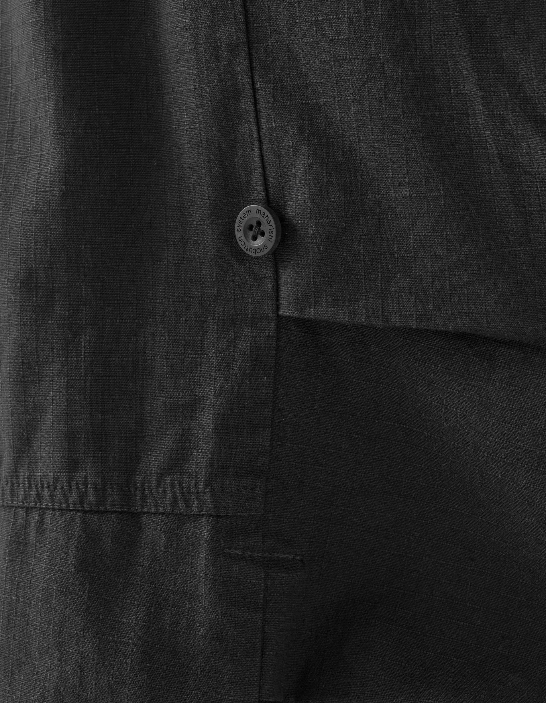 Close-up of a dark gray shirt with a button on a black background
