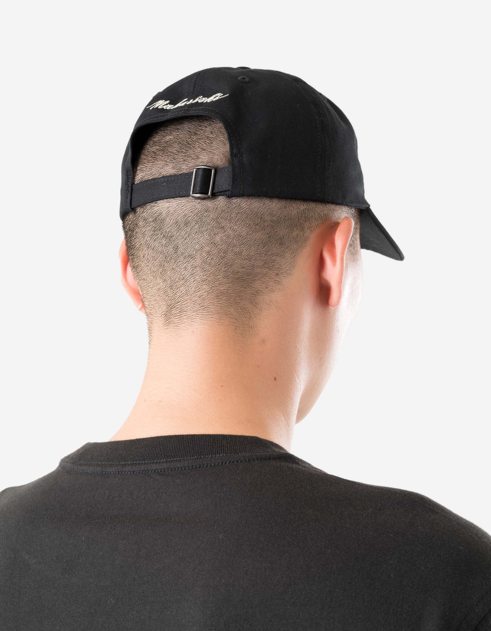 Person wearing a black cap with text on the back, facing away from the camera.