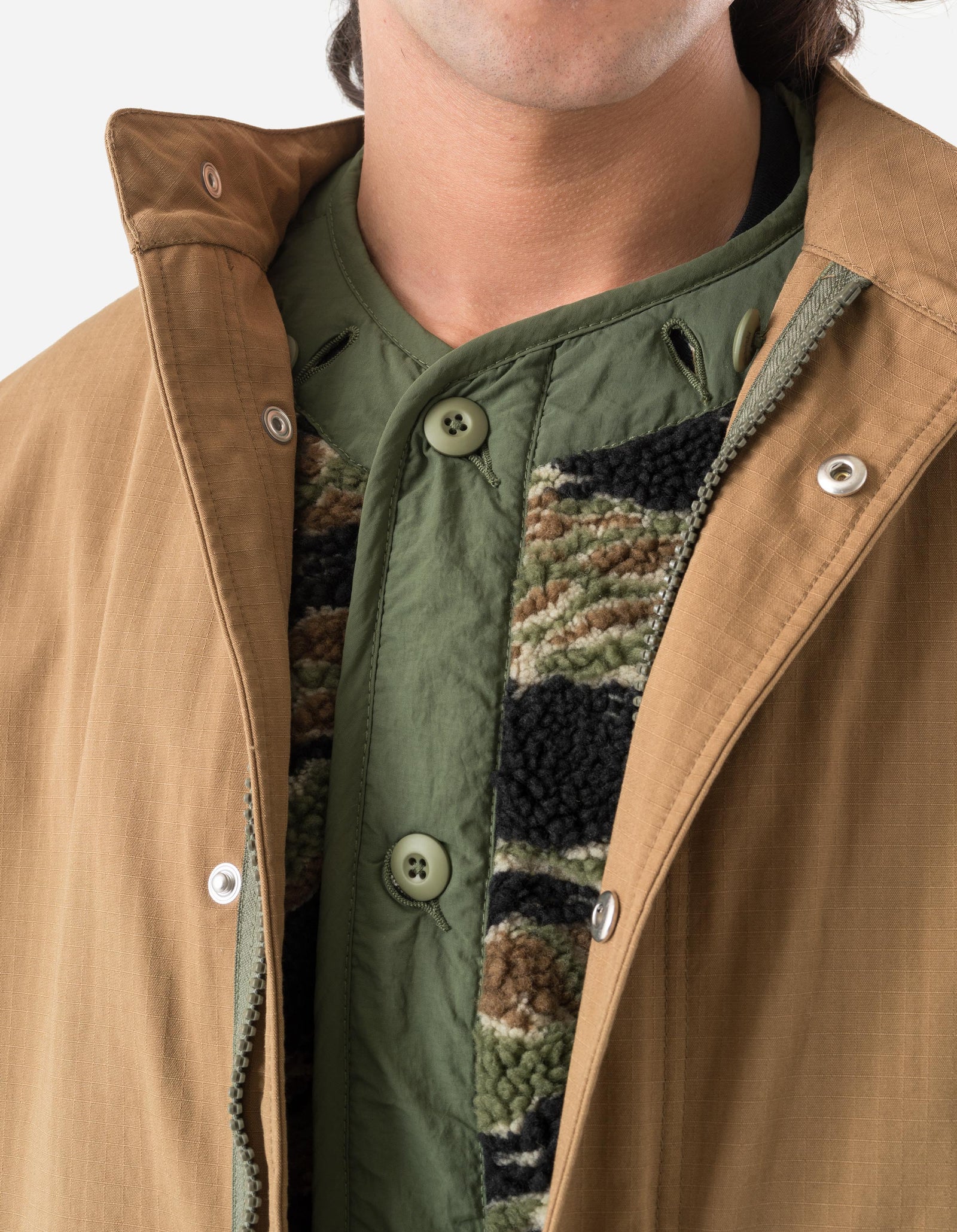 Close-up of a person wearing a brown jacket with a green quilted lining.