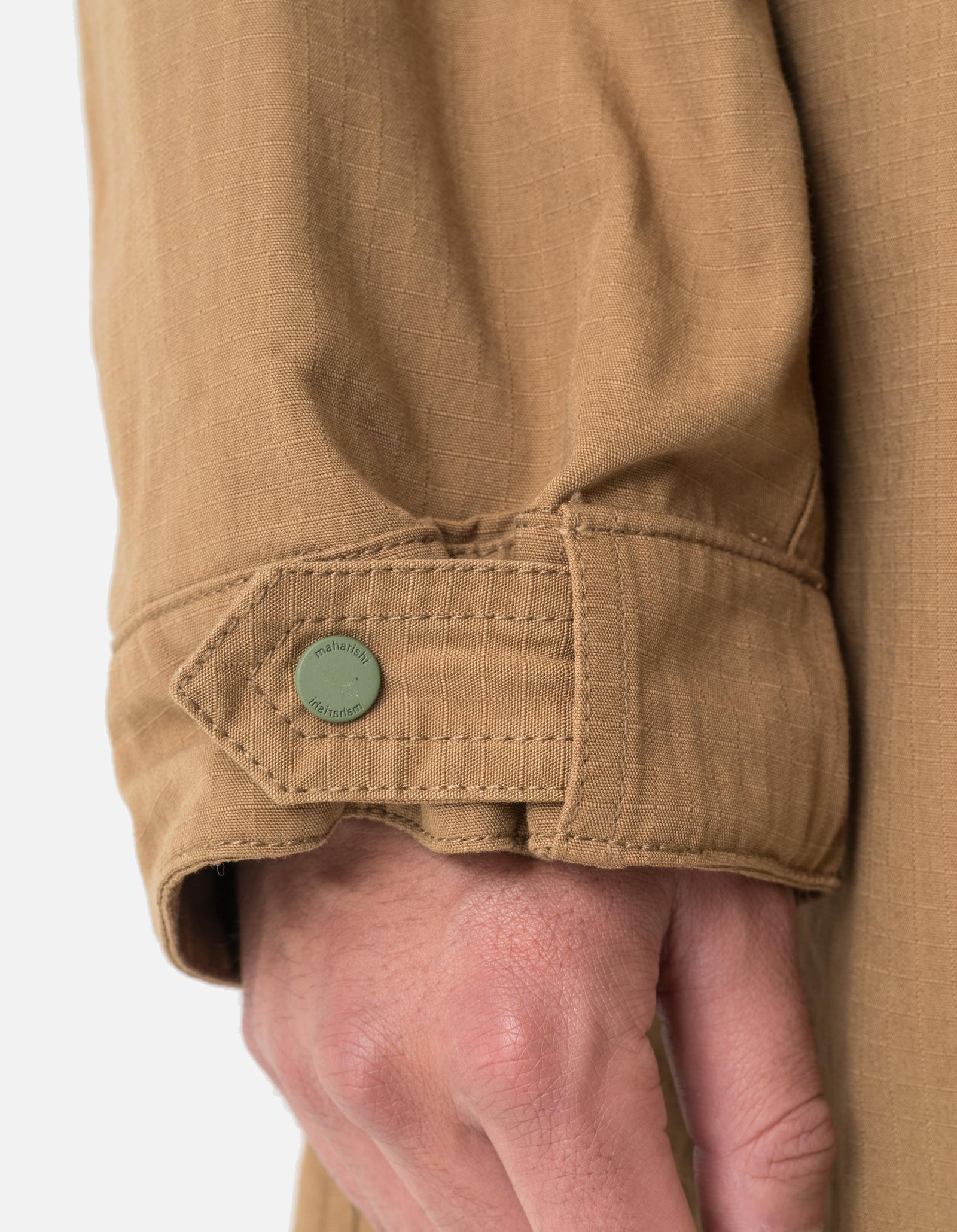Close-up of a person wearing a beige jacket with a button on a white background