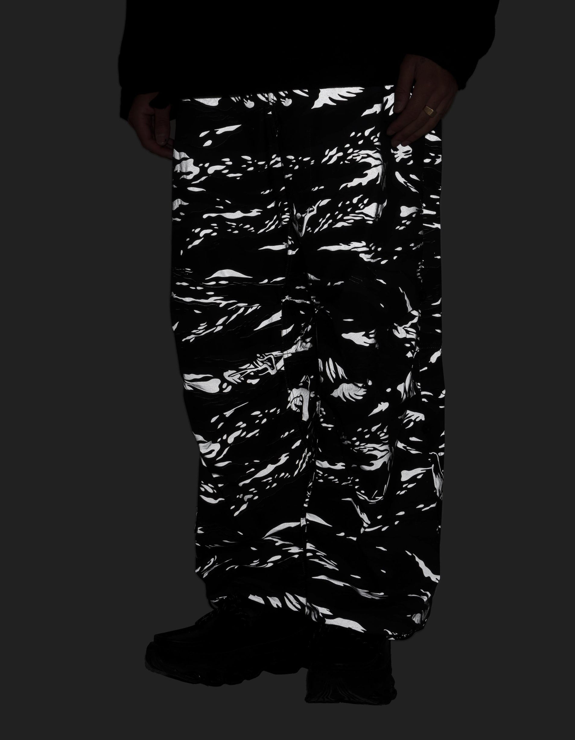Black and white camouflage pants worn by a person on a black background