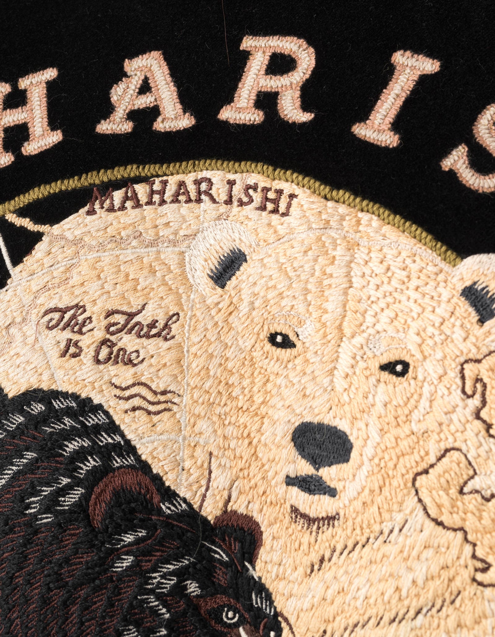 Embroidered design with bears and text on a black background, featuring the brand 'Maharishi'.