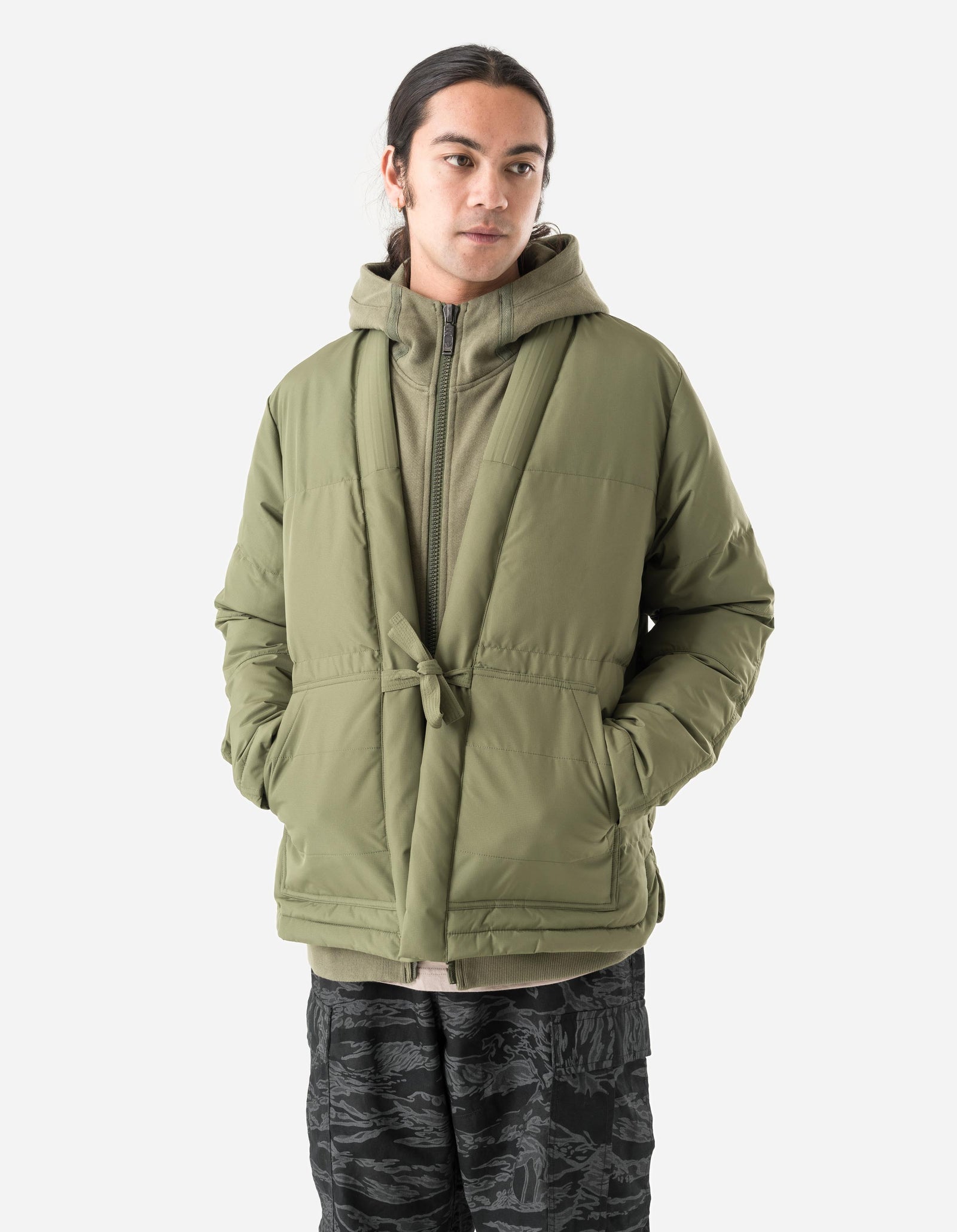 Person wearing a green puffer jacket on a white background