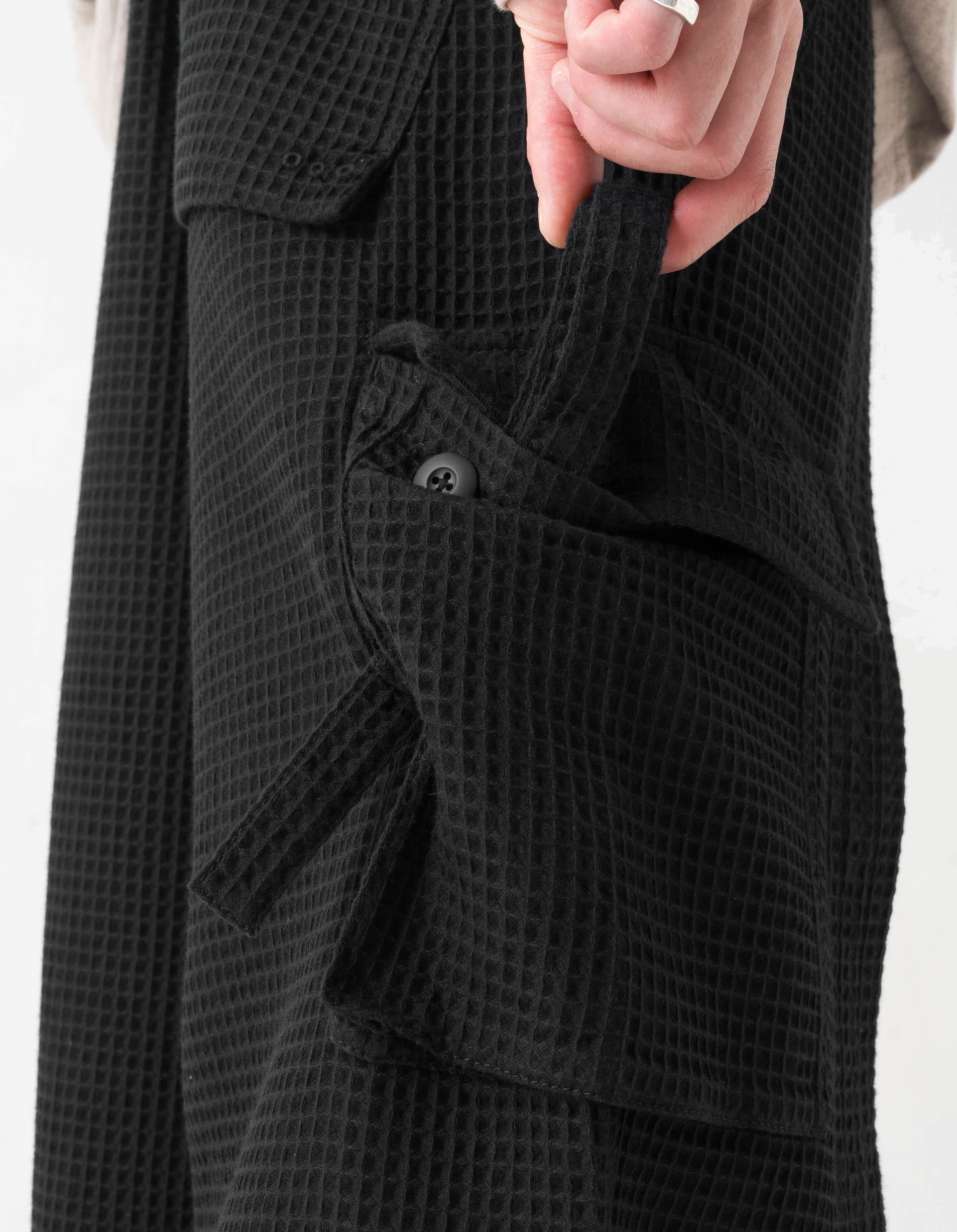 Close-up of a black textured coat with a white background