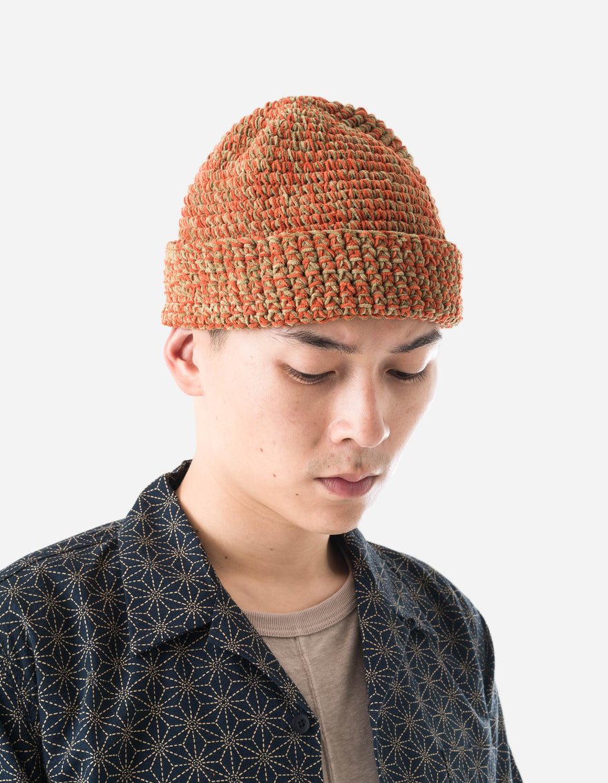 Person wearing a patterned beanie and jacket on a white background