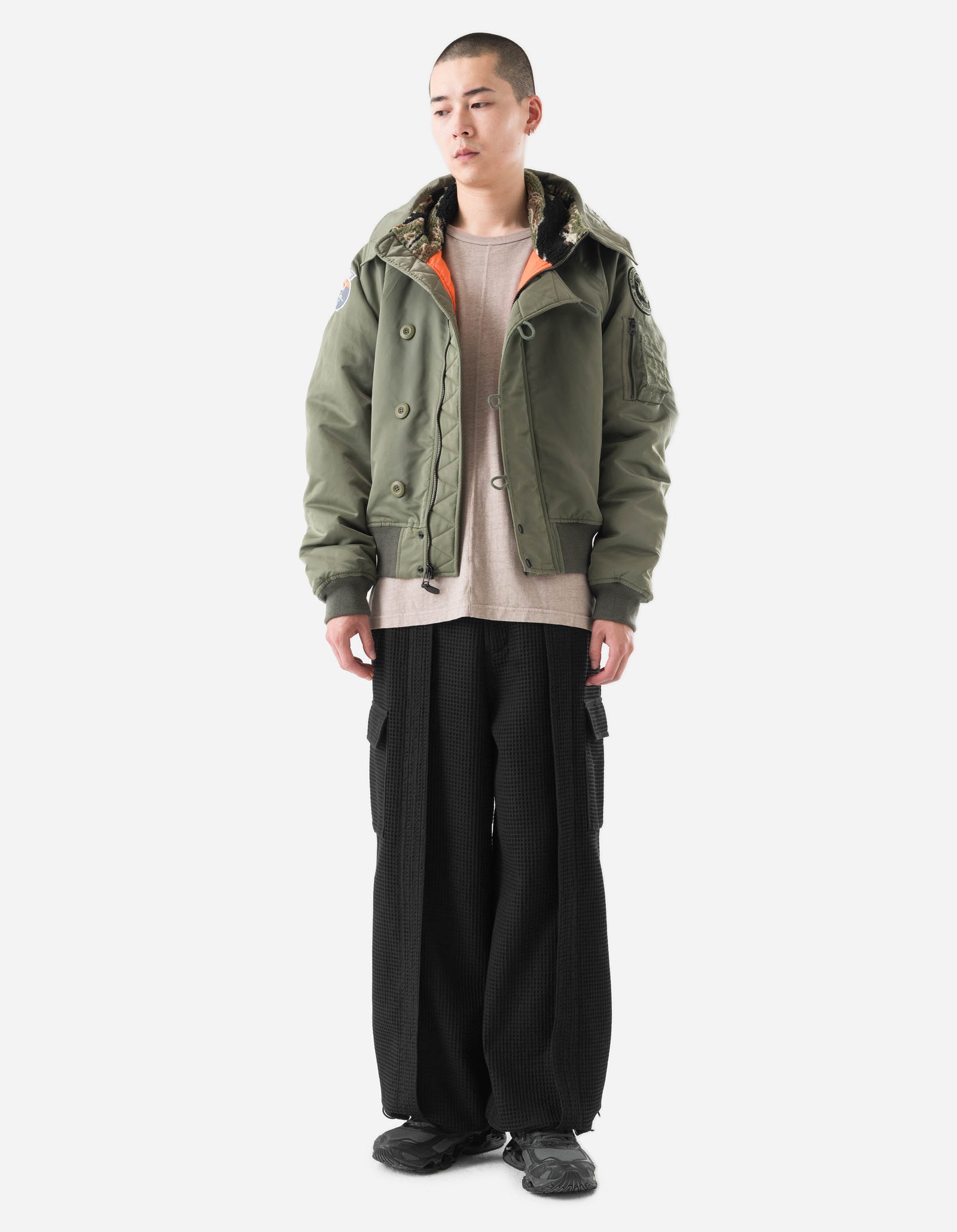 Person wearing a green jacket and black pants on a white background
