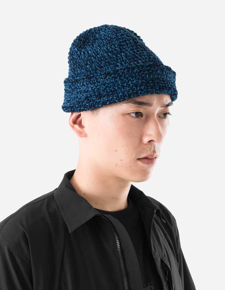 Person wearing a blue knitted beanie against a white background