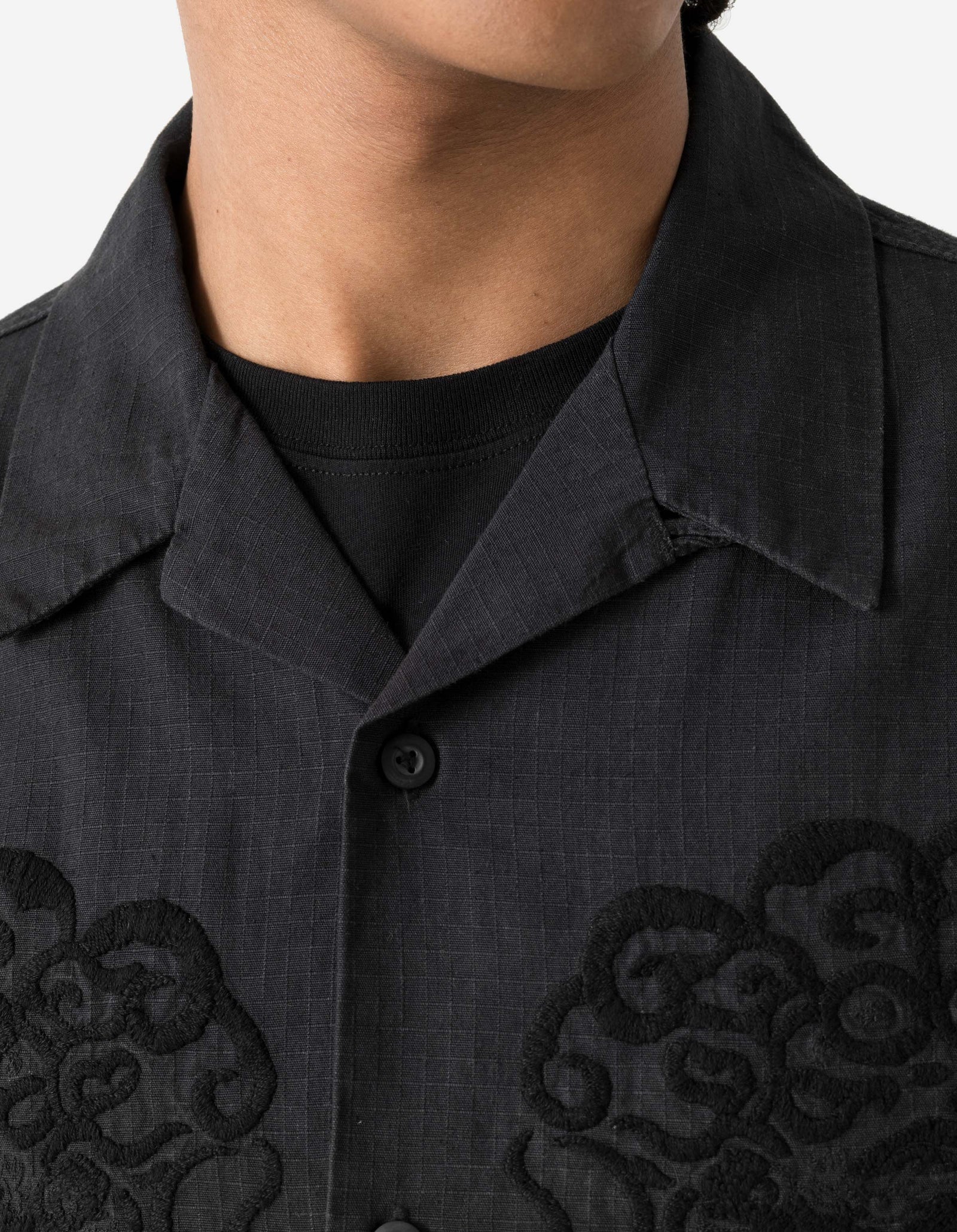 Close-up of a black shirt with intricate designs on a plain background