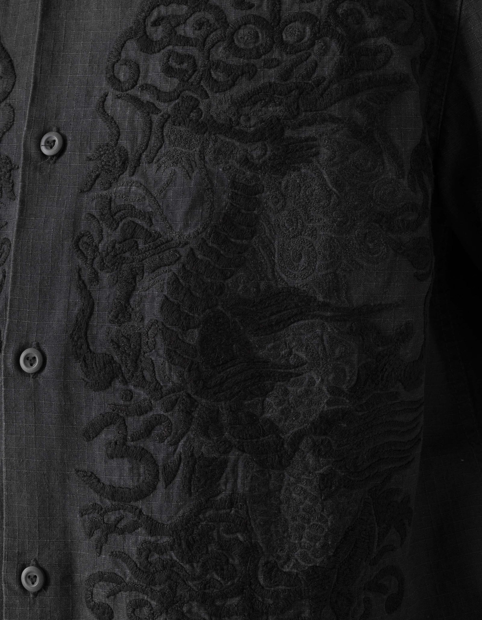 Close-up of a dark fabric with intricate embroidery on a black background