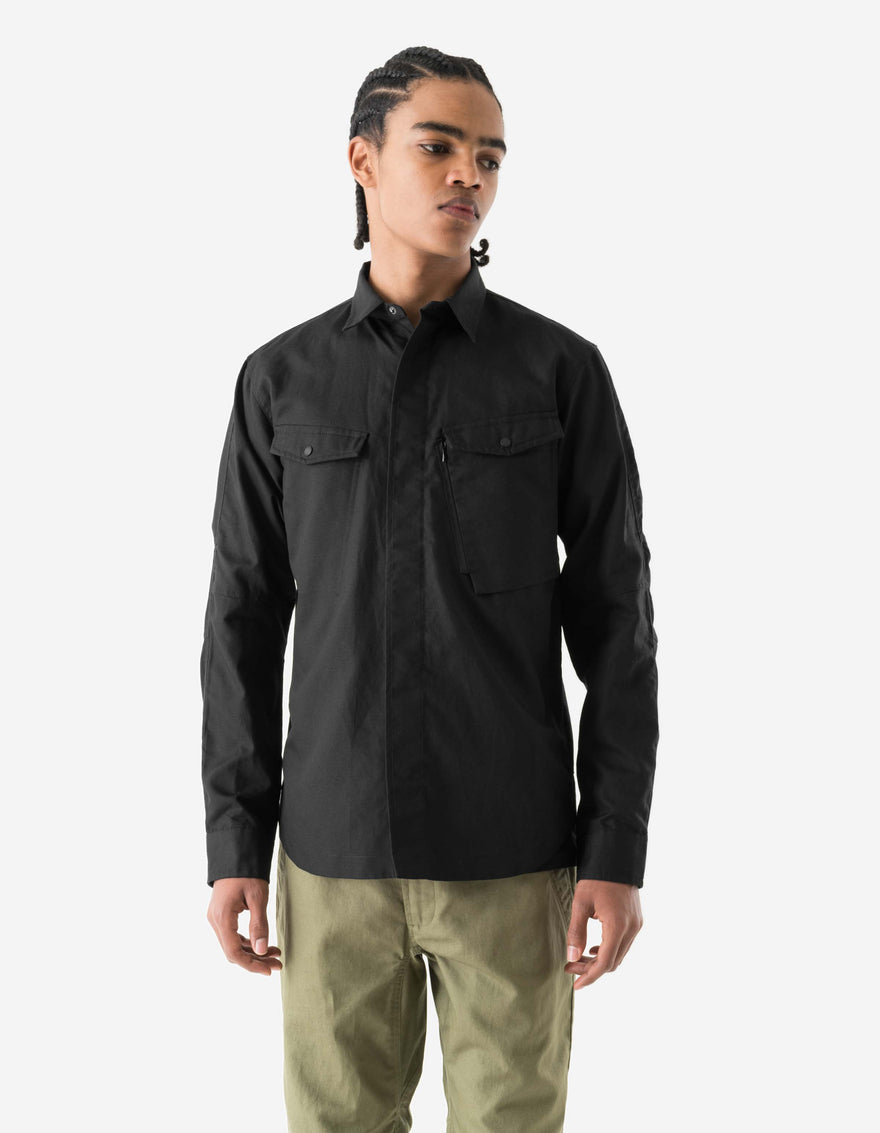 Person wearing a black long-sleeve shirt and beige pants on a white background