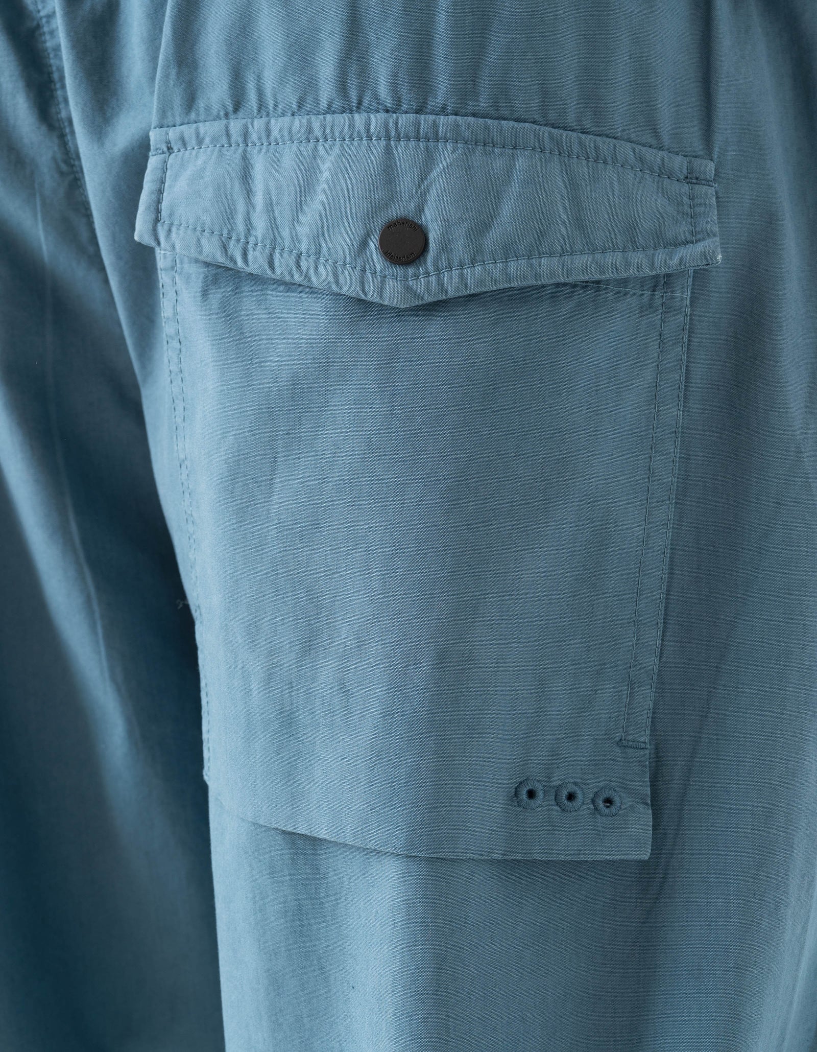 Close-up of a blue pocket on a garment with a button.