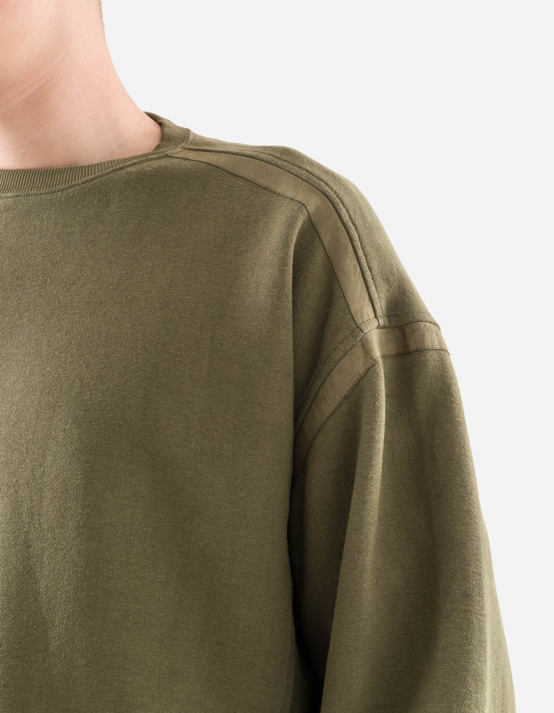 Close-up of a person wearing an olive green sweatshirt on a light gray background