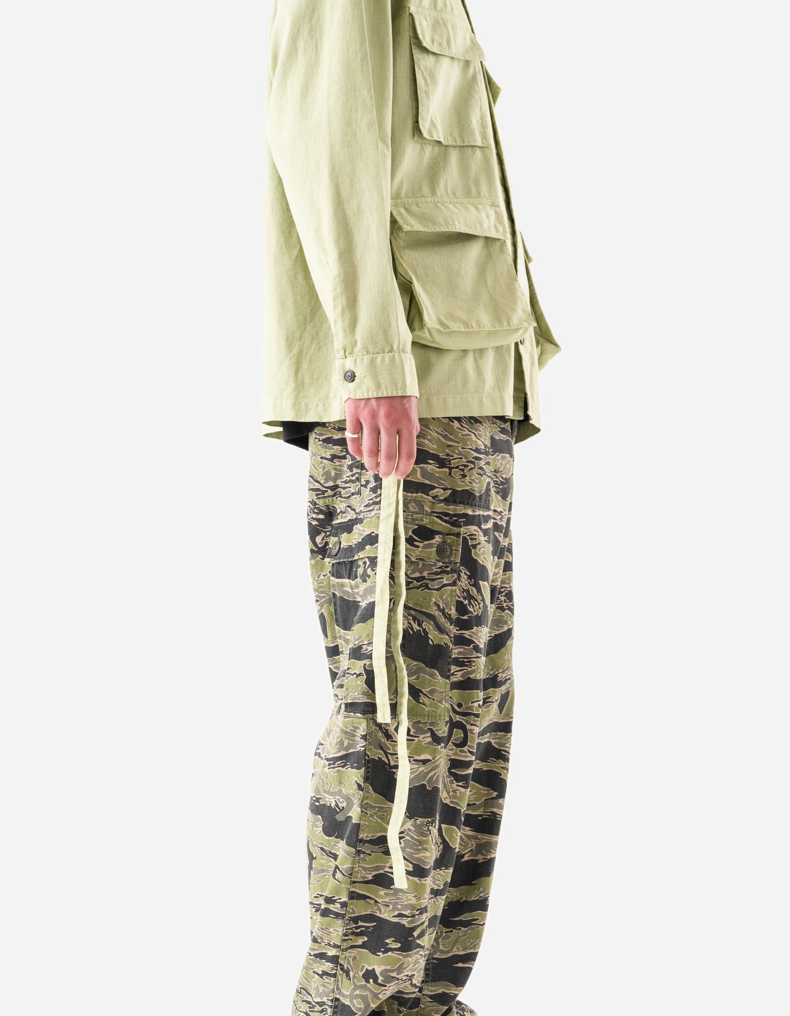 Person wearing a light green jacket and camouflage pants on a white background