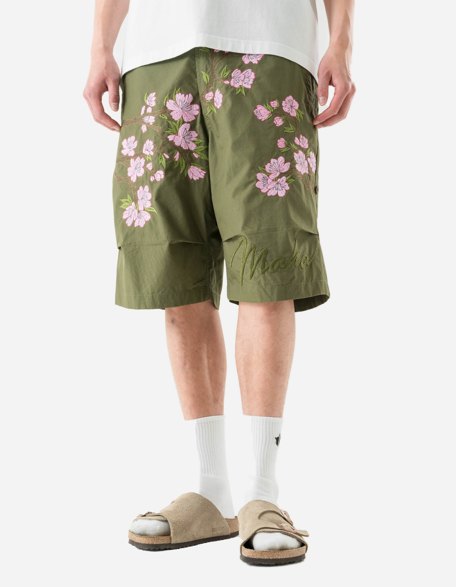 Person wearing green shorts with pink floral patterns on a white background