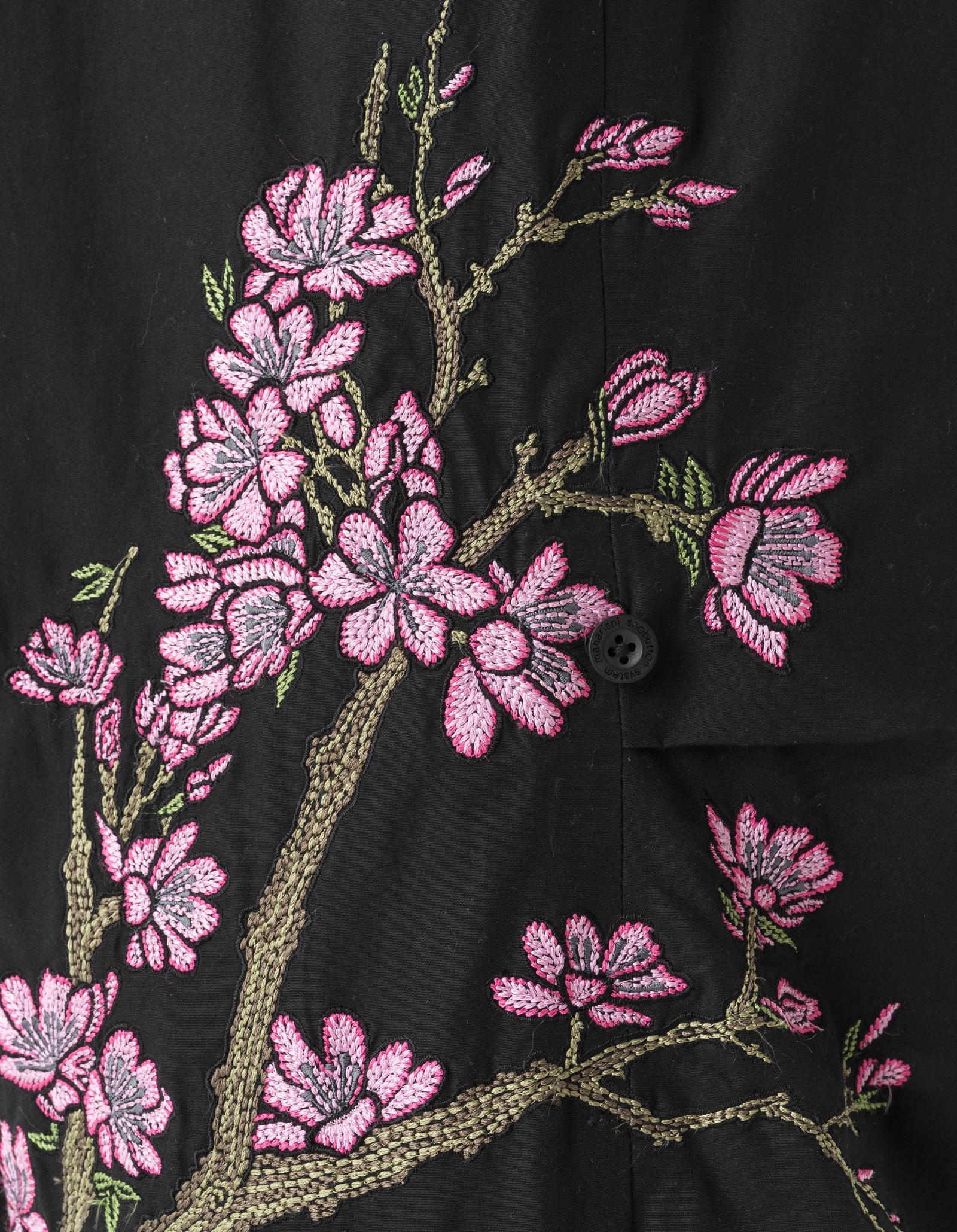 Black fabric with pink floral embroidery on a dark background